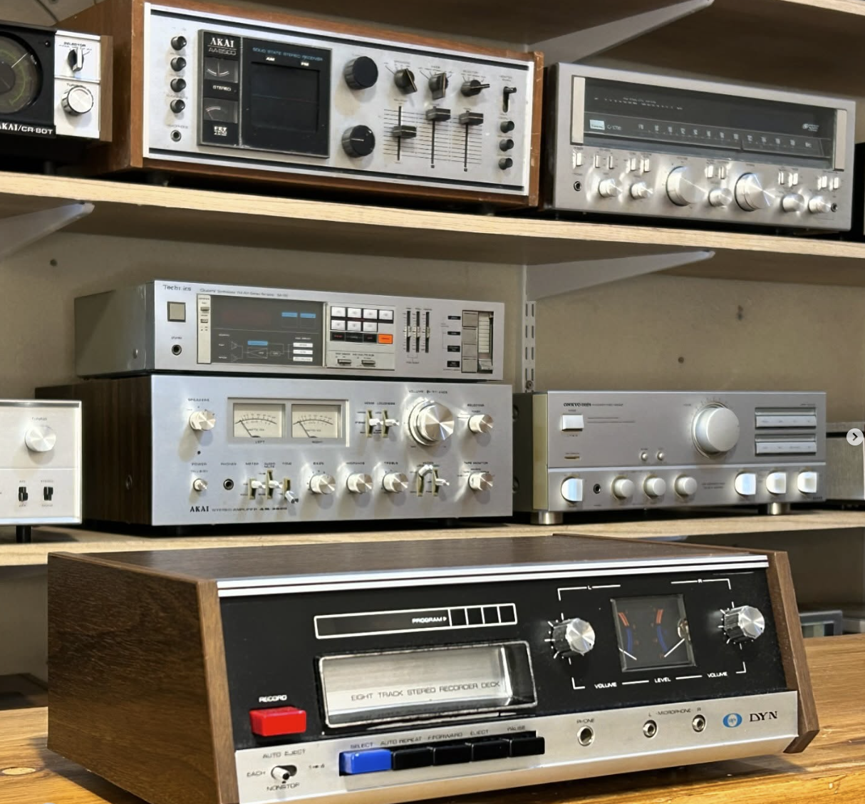 Receptores y amplificadores AKAI y Technics vintage sobre estantes de madera